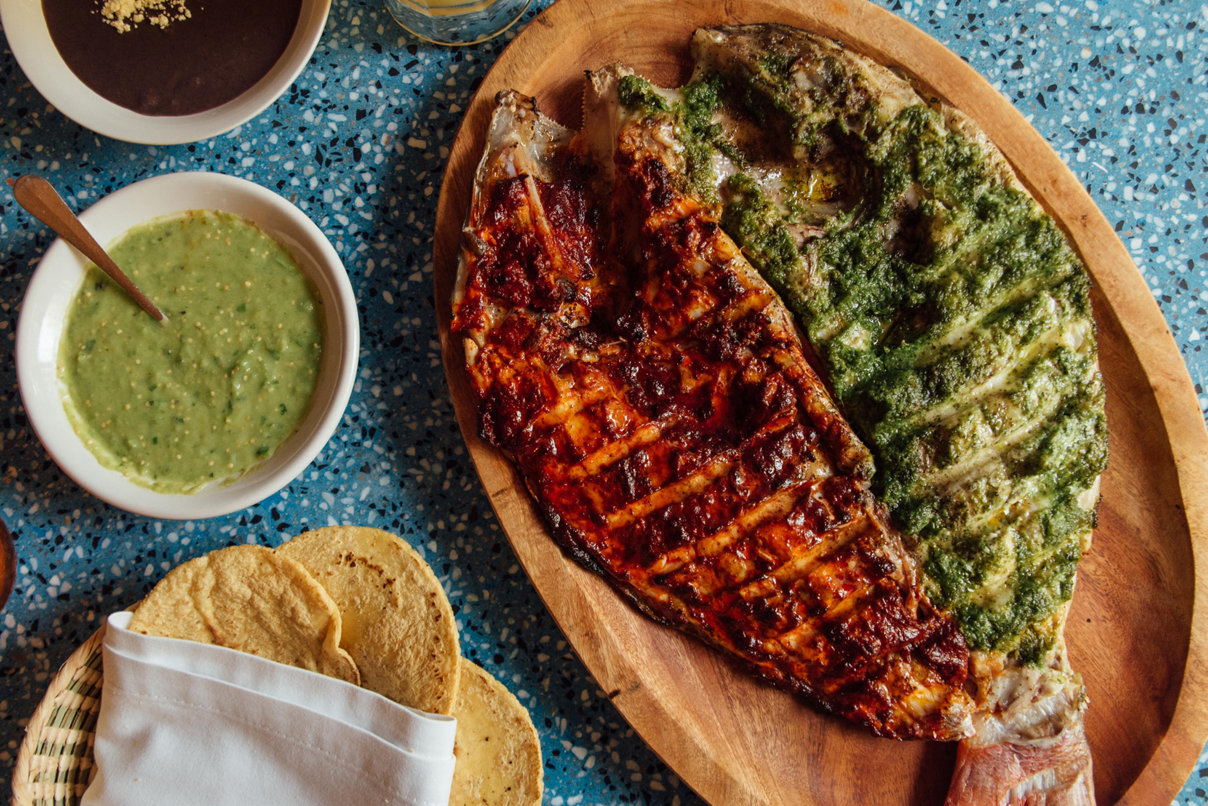 grilled fish with one half covered in red sauce and another in green
