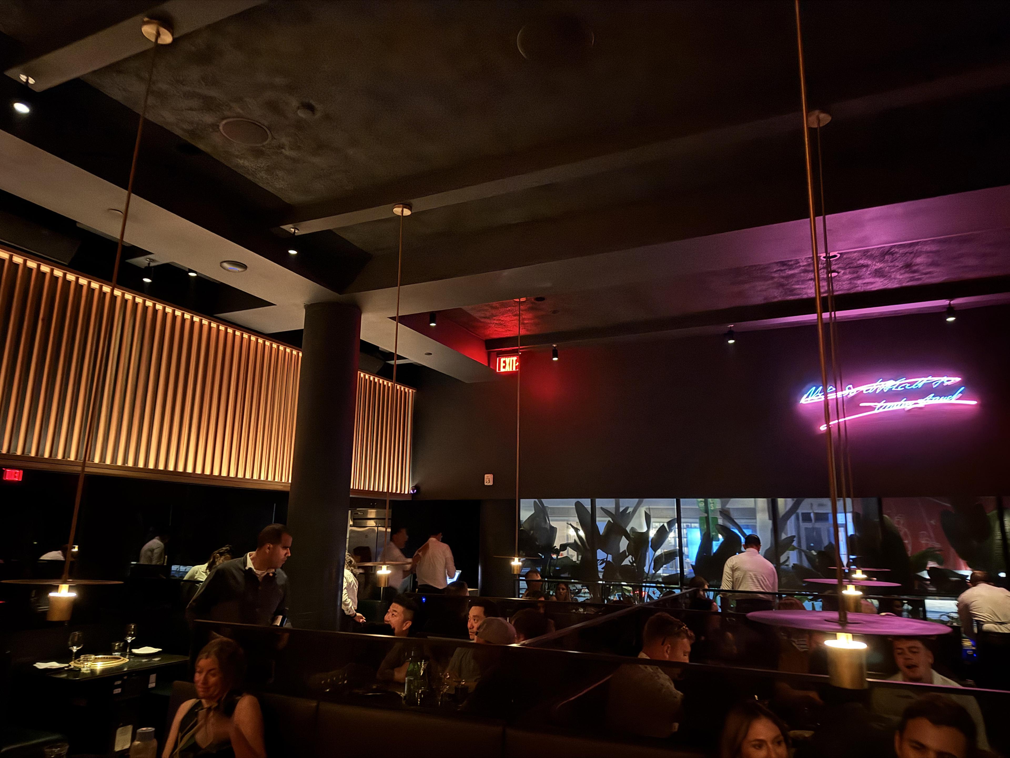 busy dark restaurant with neon sign on far wall