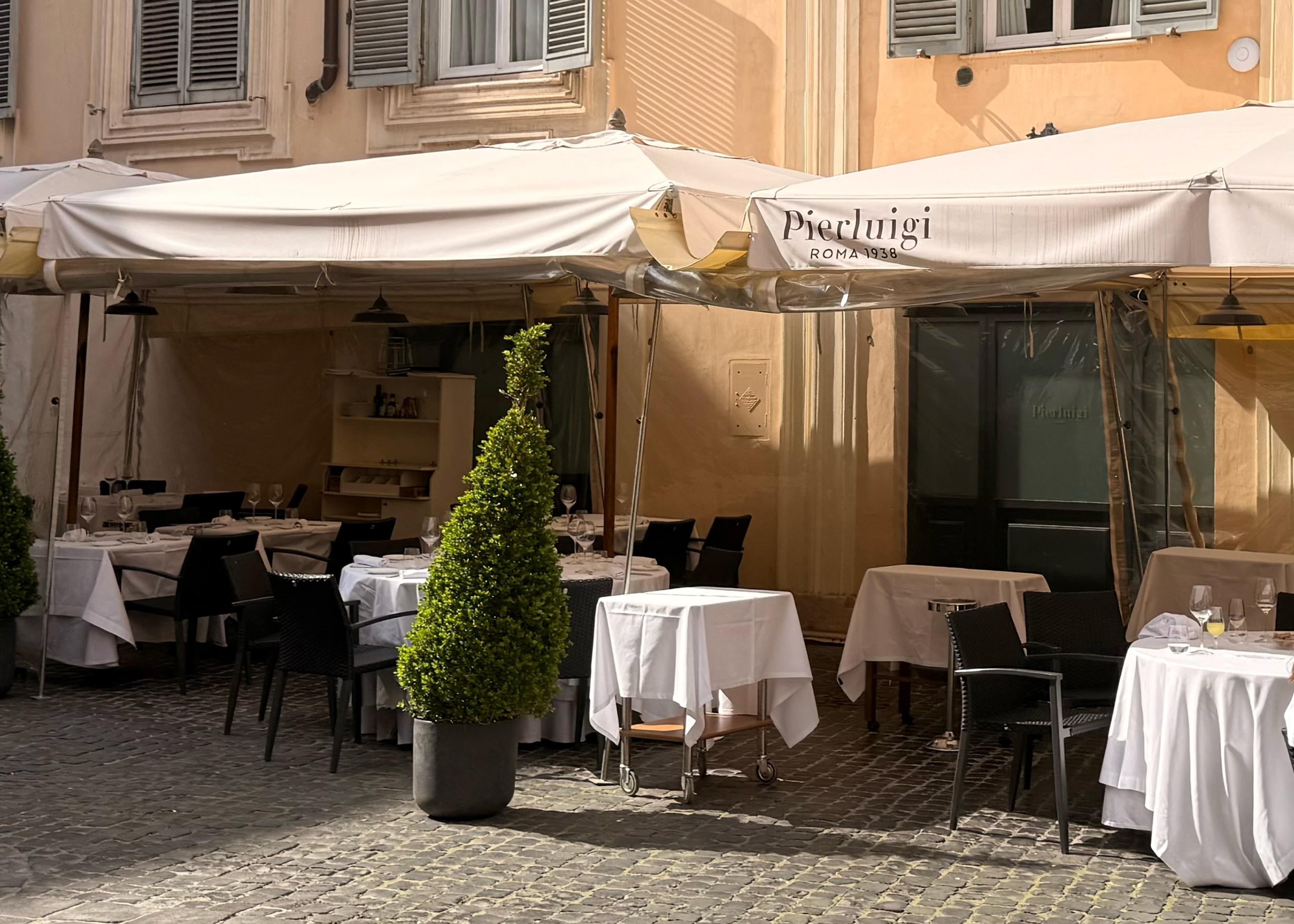 chairs out front of roman trattoria with umbrellas saying Pierluigi