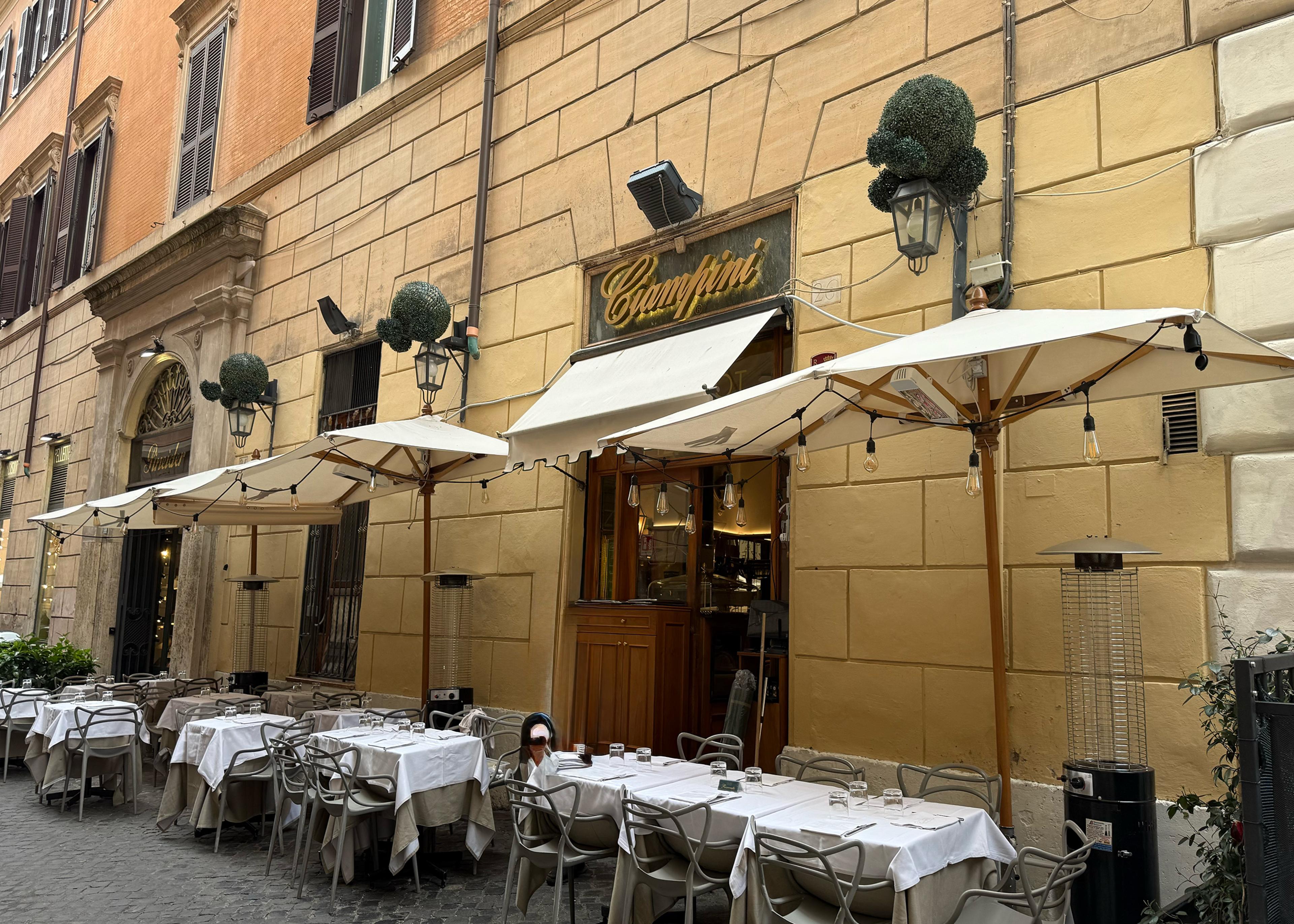 exterior of bistro in rome with exterior seating under umbrellas