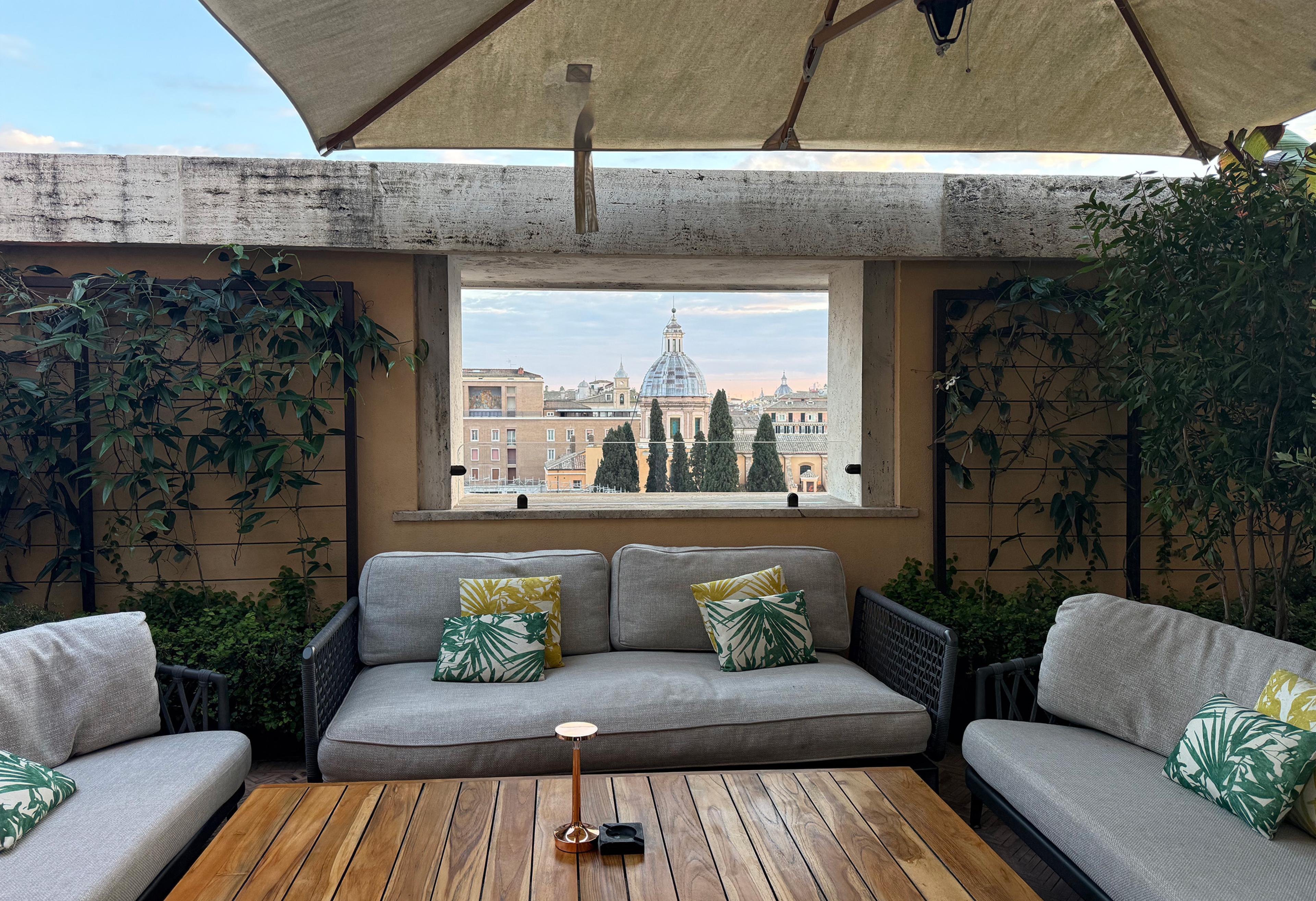 outdoor lounge seating on roman roof with open-air window with view over rooftops