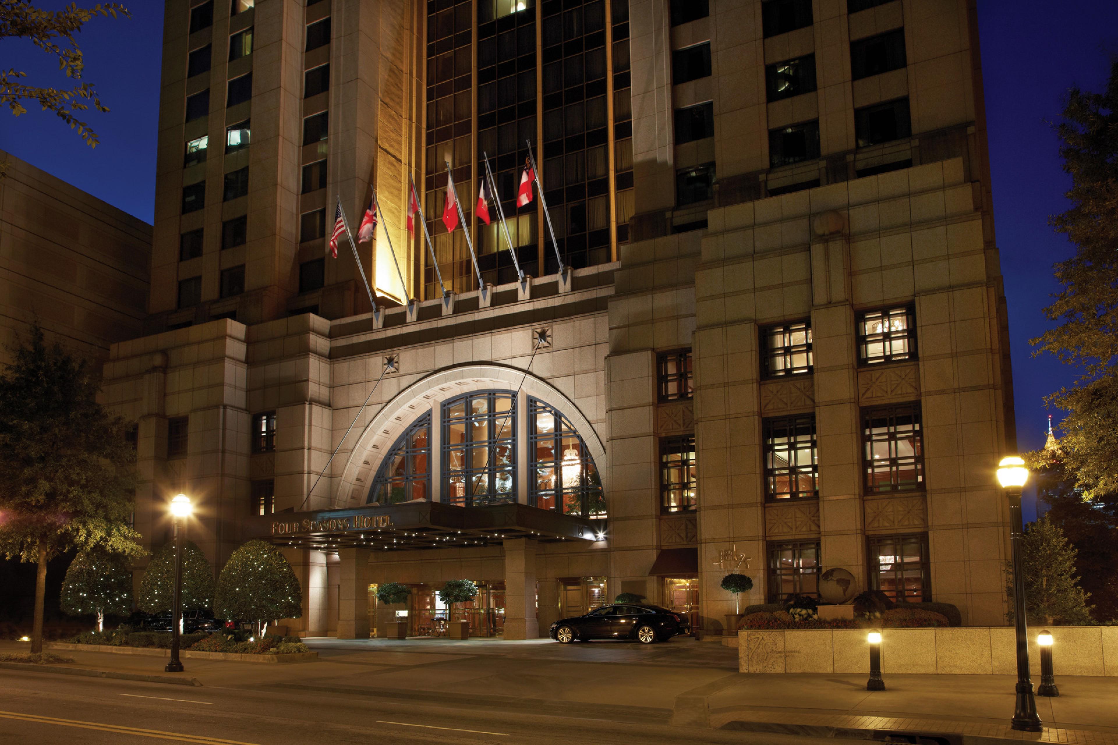 exterior of city skyscraper at night with hotel entrance with flags above entrance