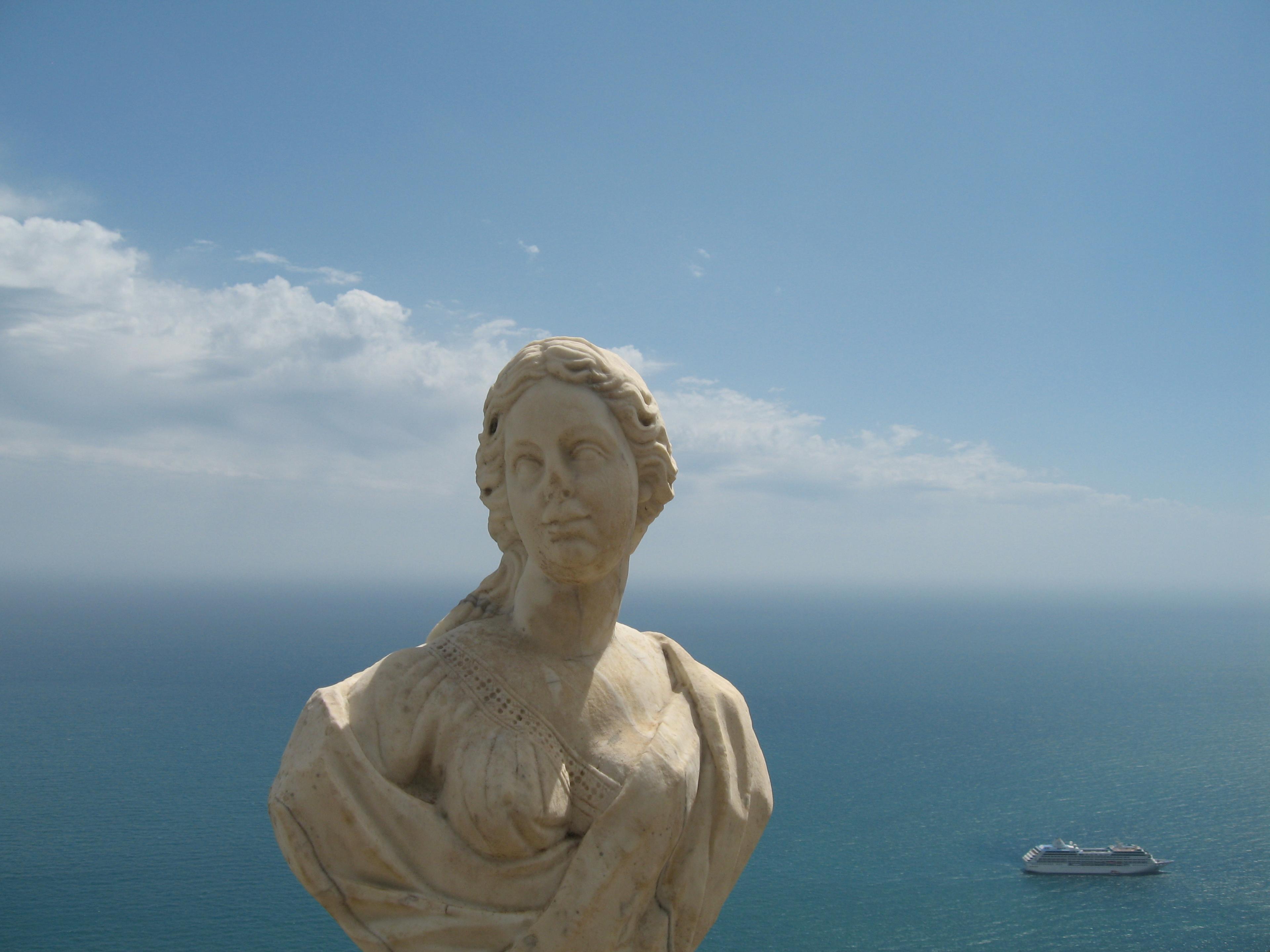 historic stone bust of woman outside on sunny day with sea viewed below