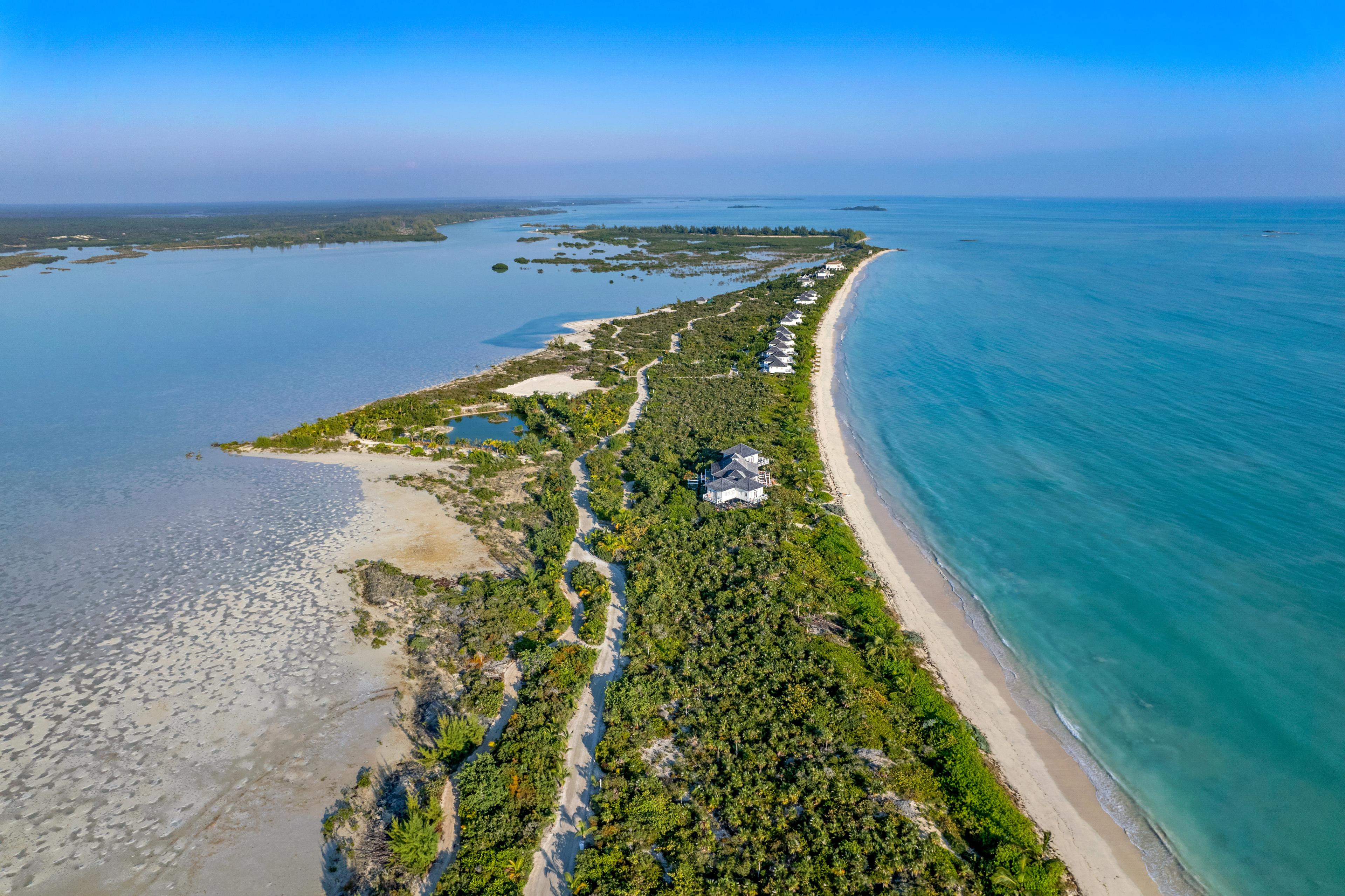 Aerial view of turquoise coastline with sandy beaches, green islands, lagoons, and scattered seaside homes.