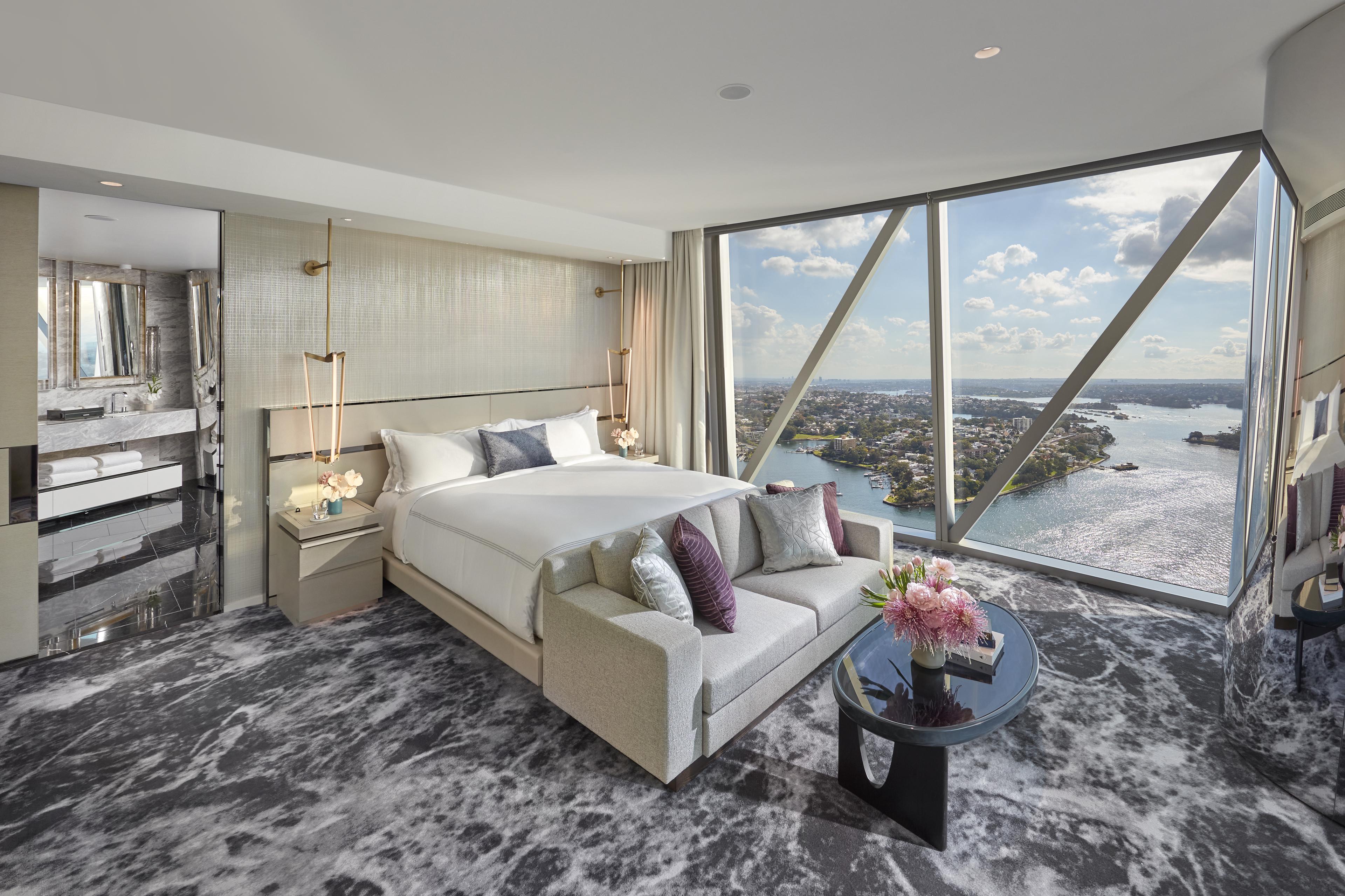 Luxury high-rise bedroom with marble bath, floor-to-ceiling windows, and sweeping harbor city views