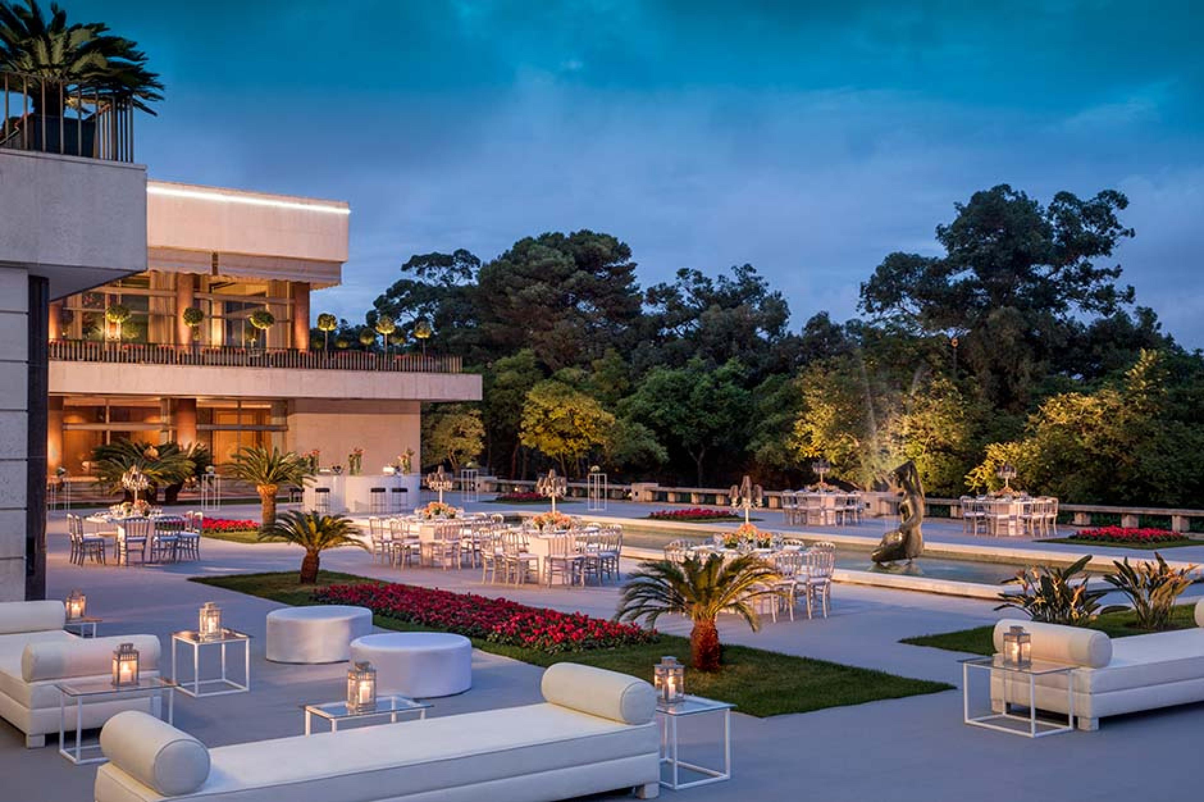 hotel exterior with tables, chairs, and a water feature