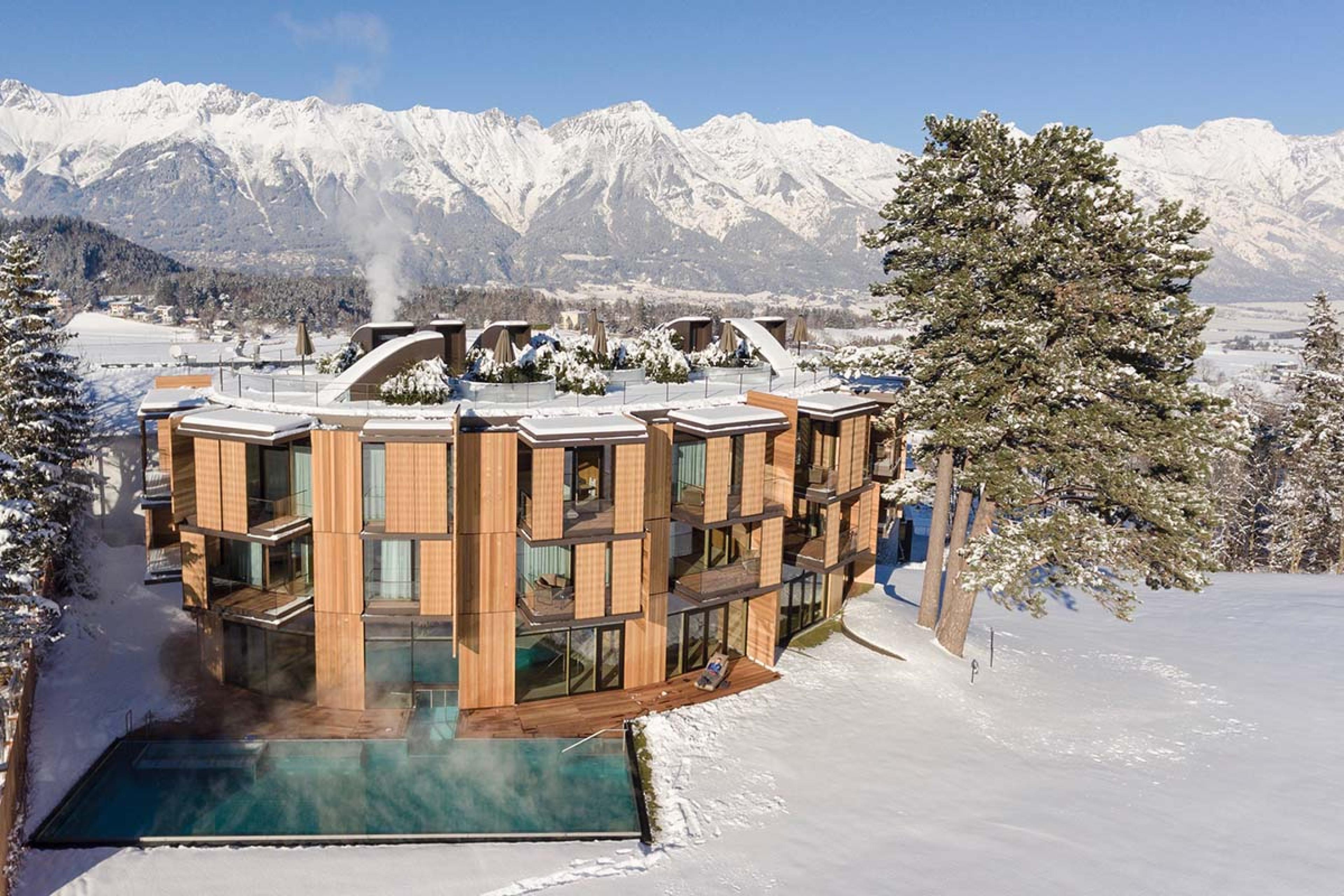 wooden building with a heated pool surrounded by snow