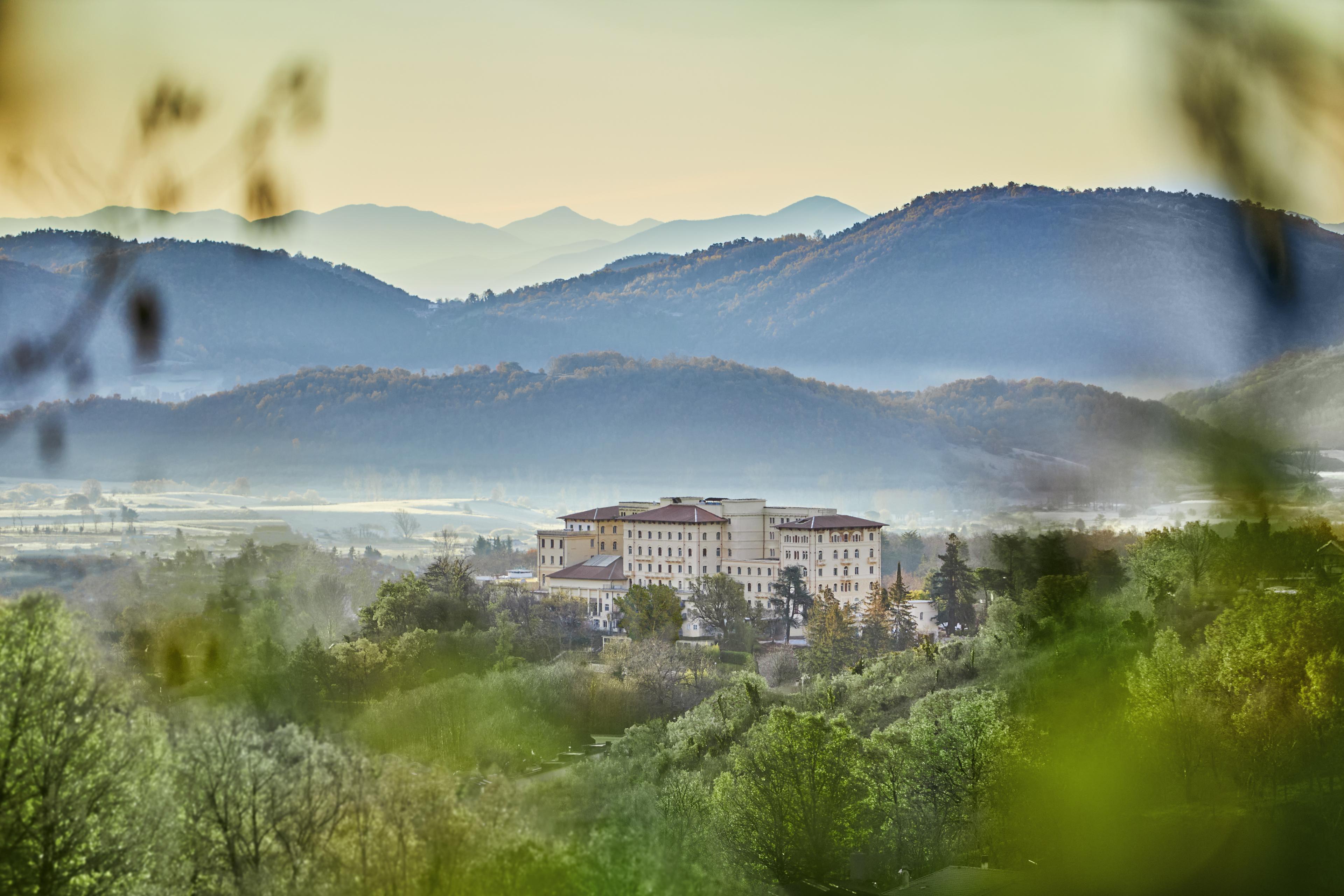 white building tucked amidst greenery and hills