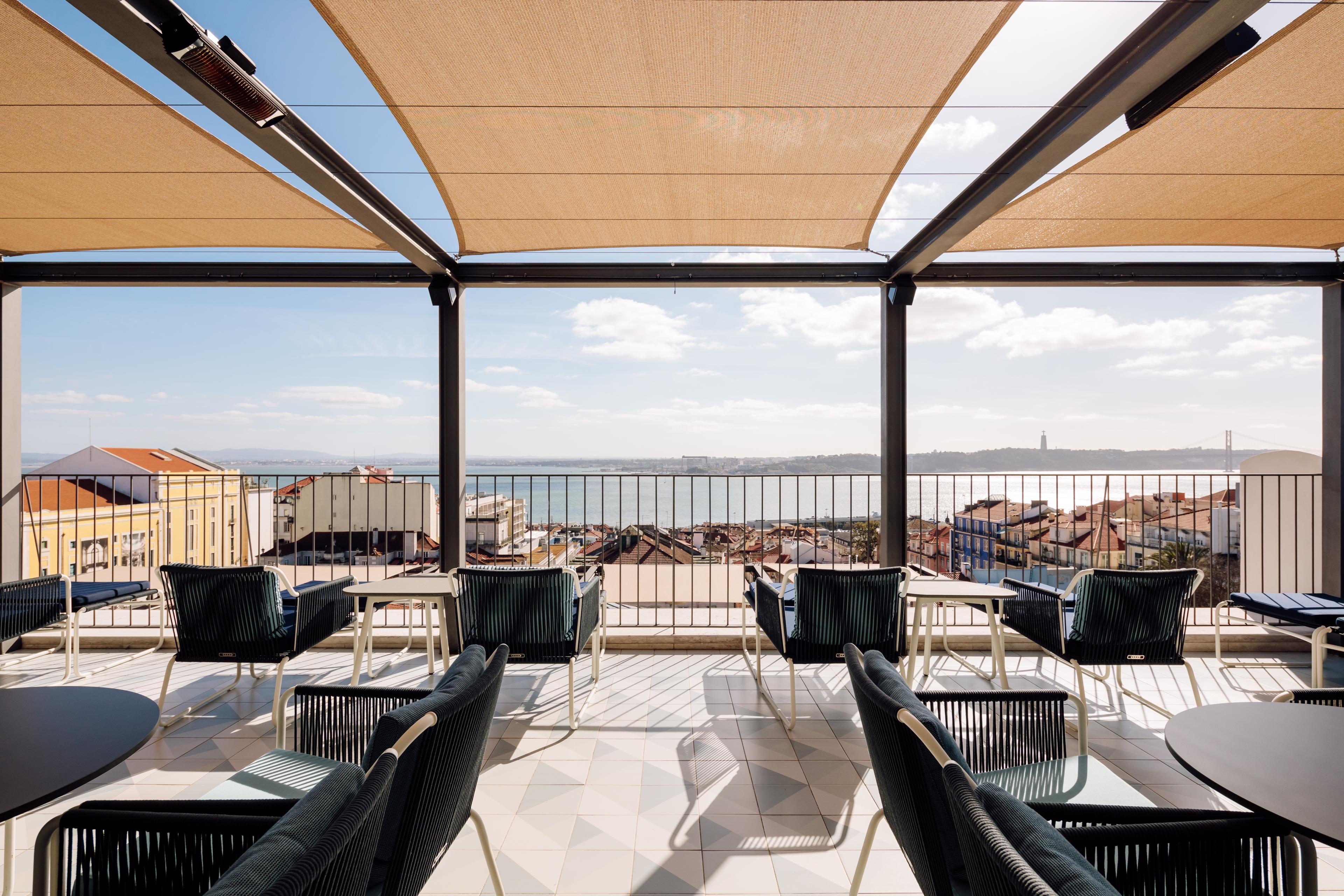 Rooftop area with tables and chairs and a view of Lisbon 