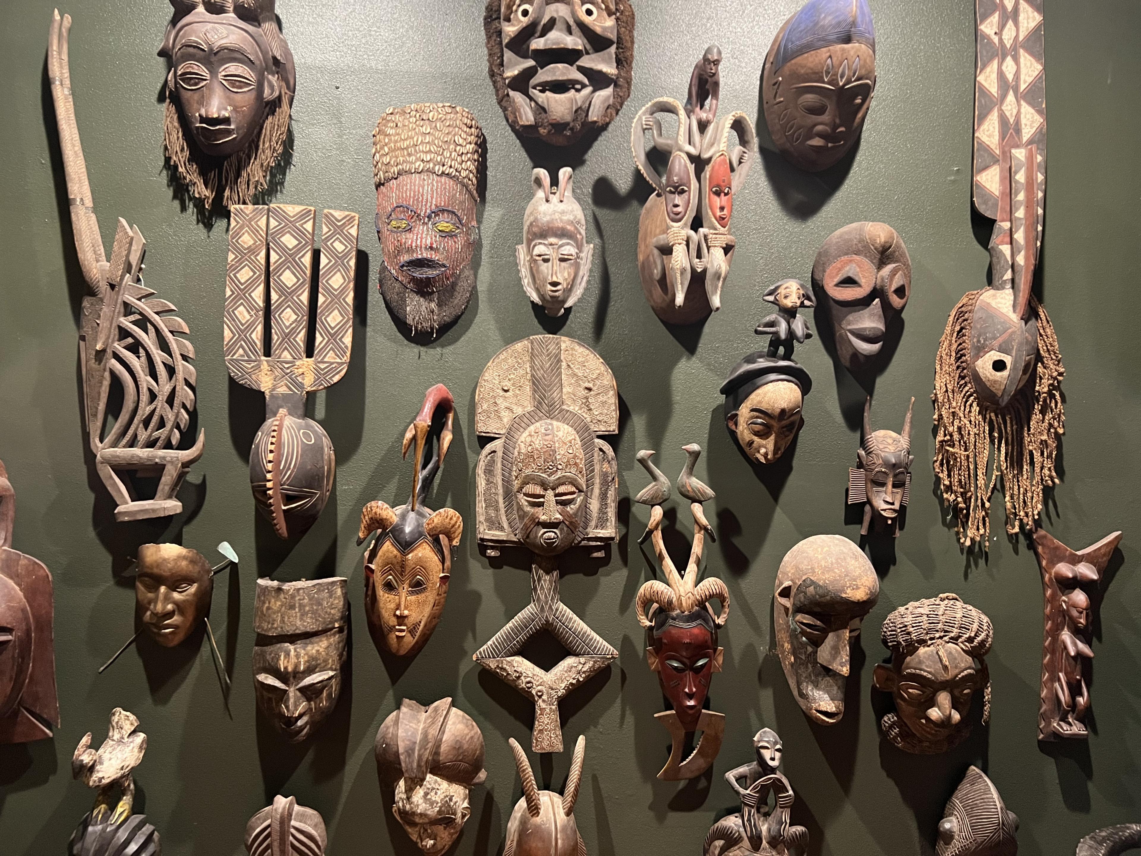 african wooden face masks hanging on green wall