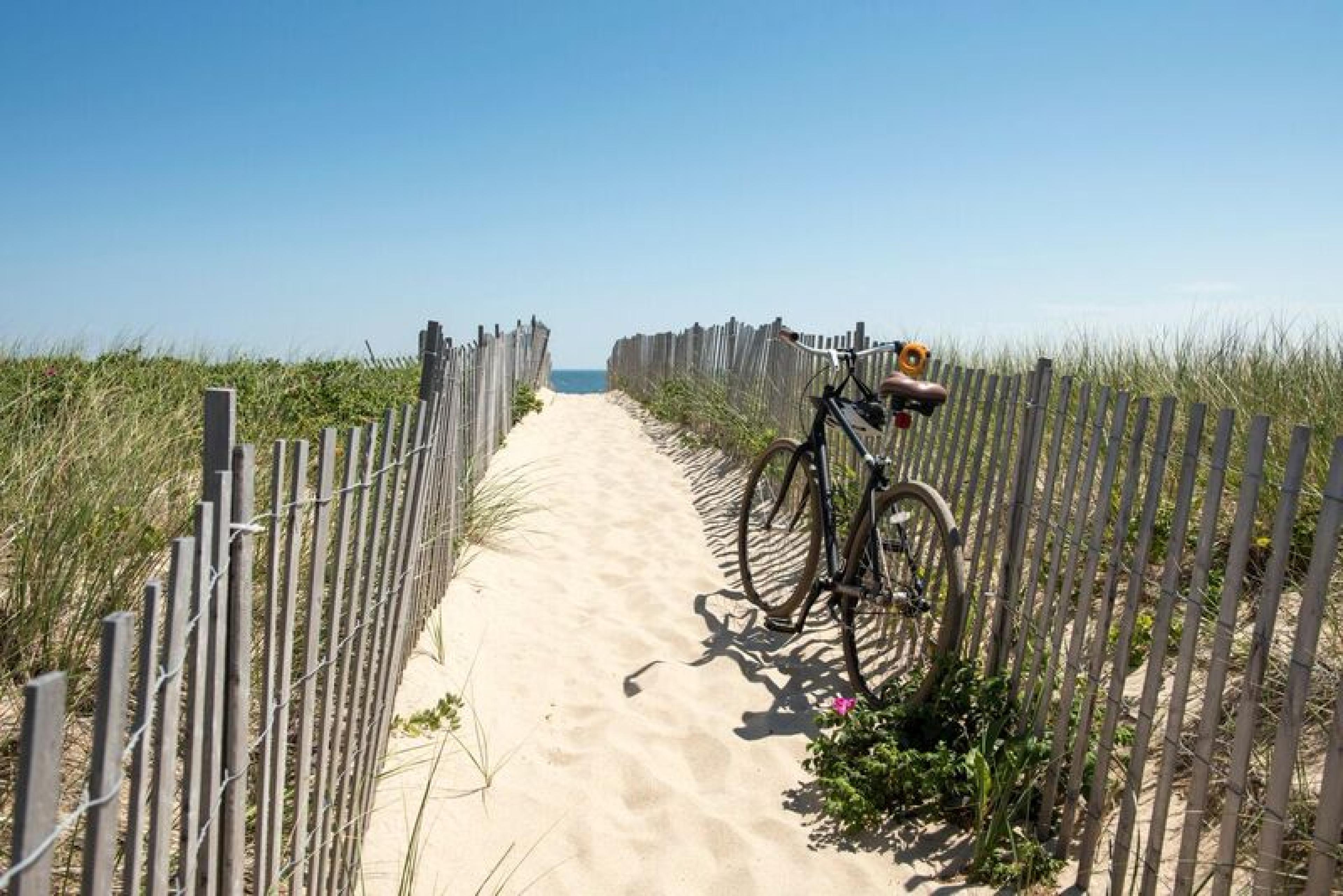 beach path through dunes to beach with ocean visible at end and a bike on the side