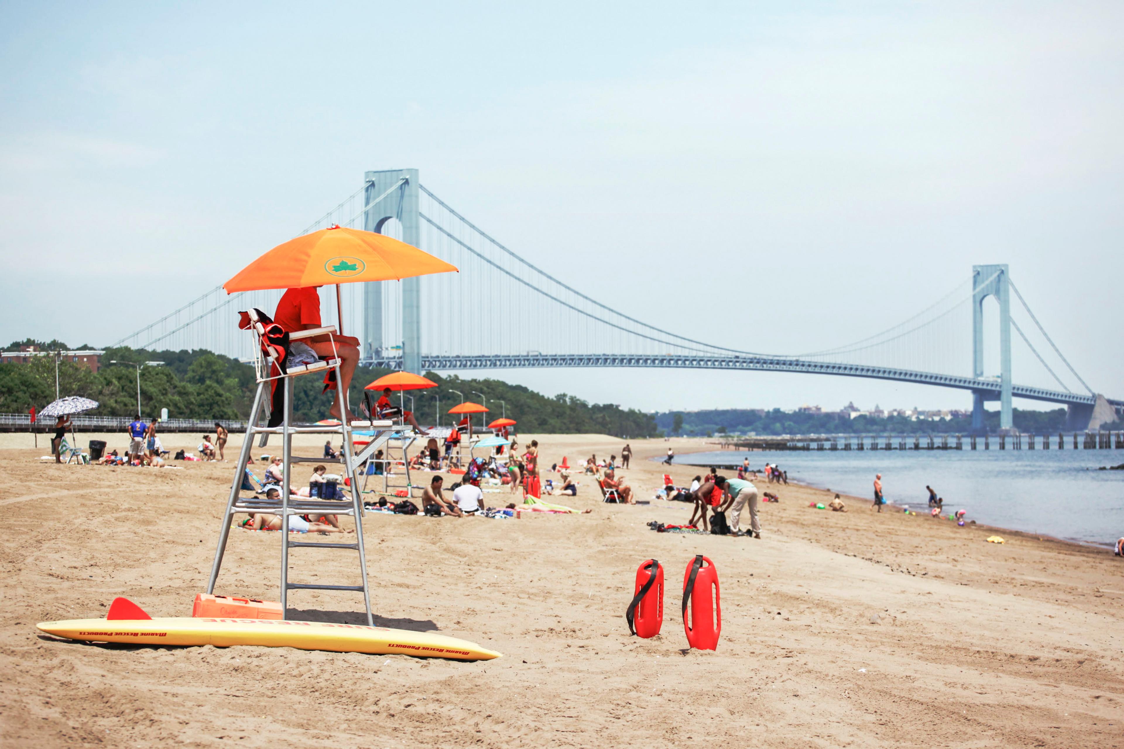 beach with water on right and large bridge in the background