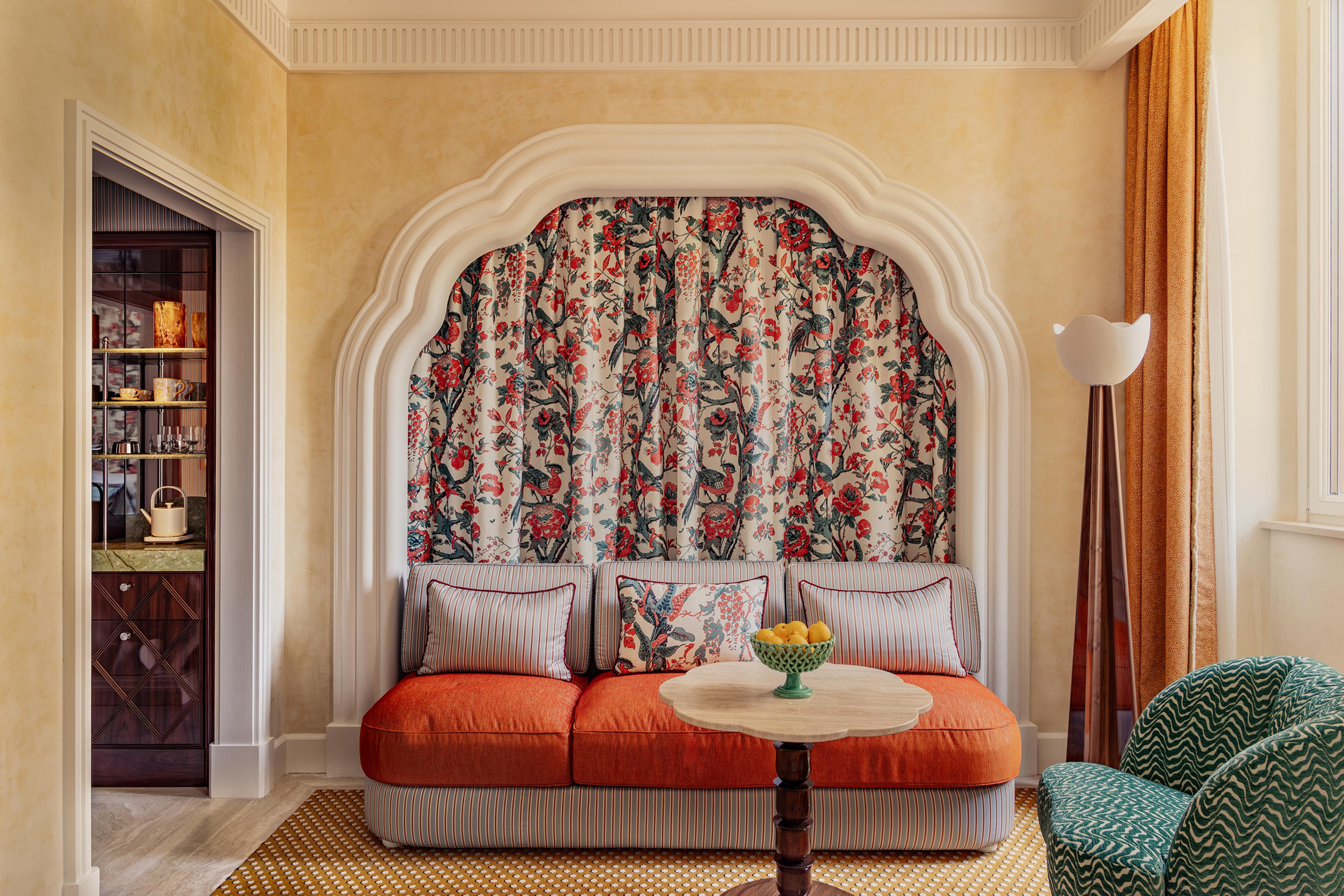 sofa in front of yellow wall with patterned red and green tapestry hanging behind it