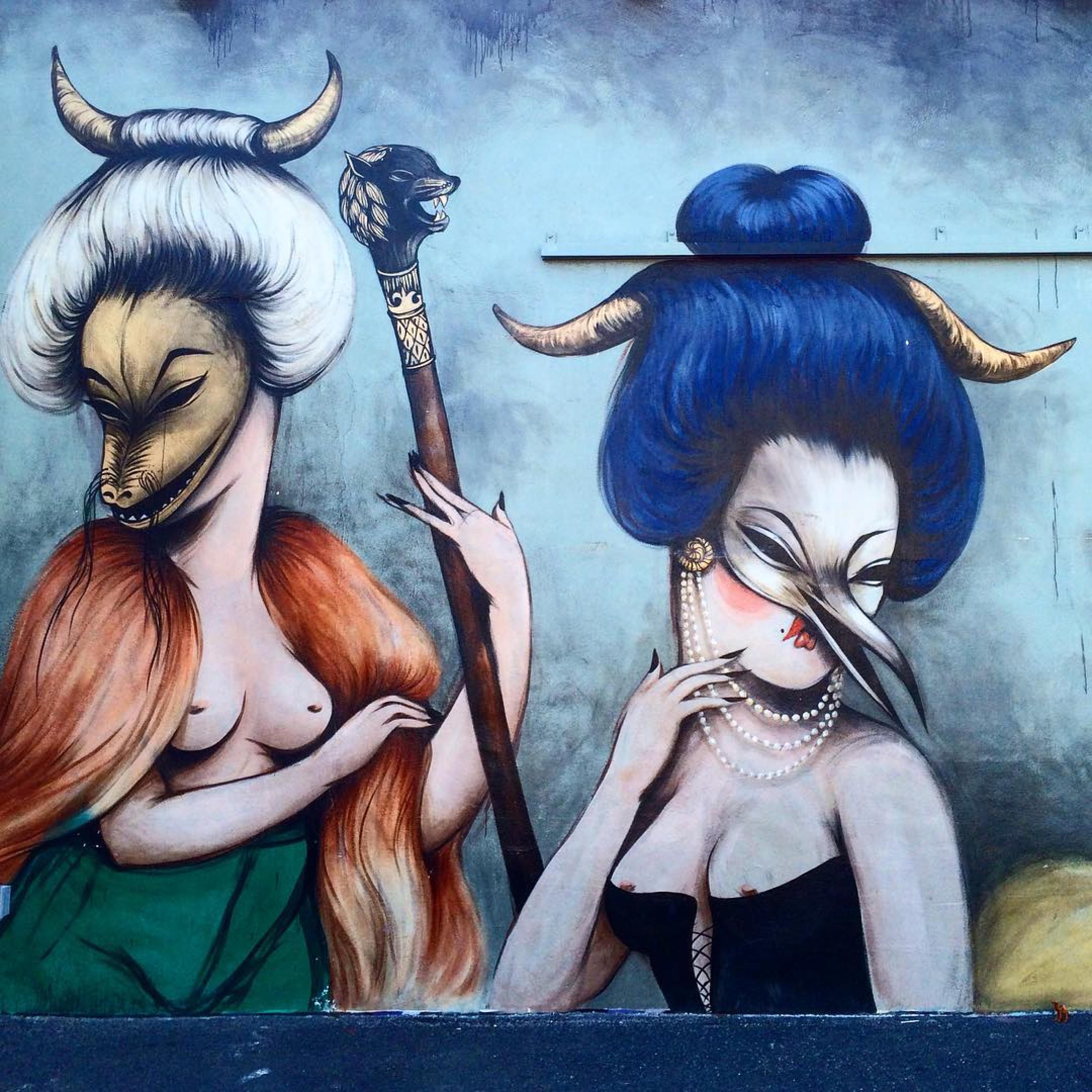 mural of two women with animal masks on and bare chests and big wigs with horns
